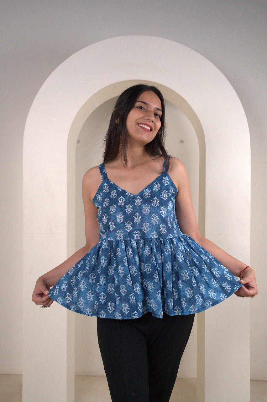 Woman wearing a blue floral dress standing in a white archway.