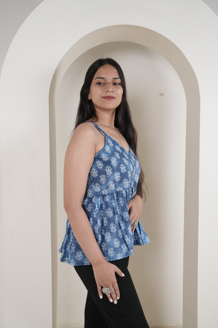 Woman wearing a blue floral top standing in front of a white archway.